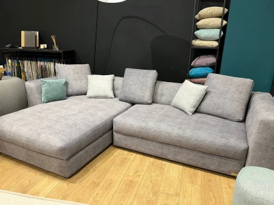 Низькопрофільний кутовий диван попелястого кольору з масивними підлокітникам