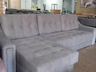 Сірий кутовий диван із каретною стяжкою на спинці та сидінні