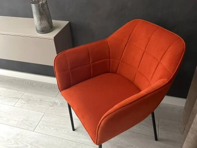 Помаранчеве м'яке крісло на тонких металевих ніжках