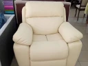 Крісло-реклайнер молочного кольору зі шкіряною оббивкою