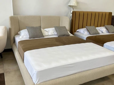 Двоспальне ліжко в тканині букле молочного кольору на високих металевих ніжках